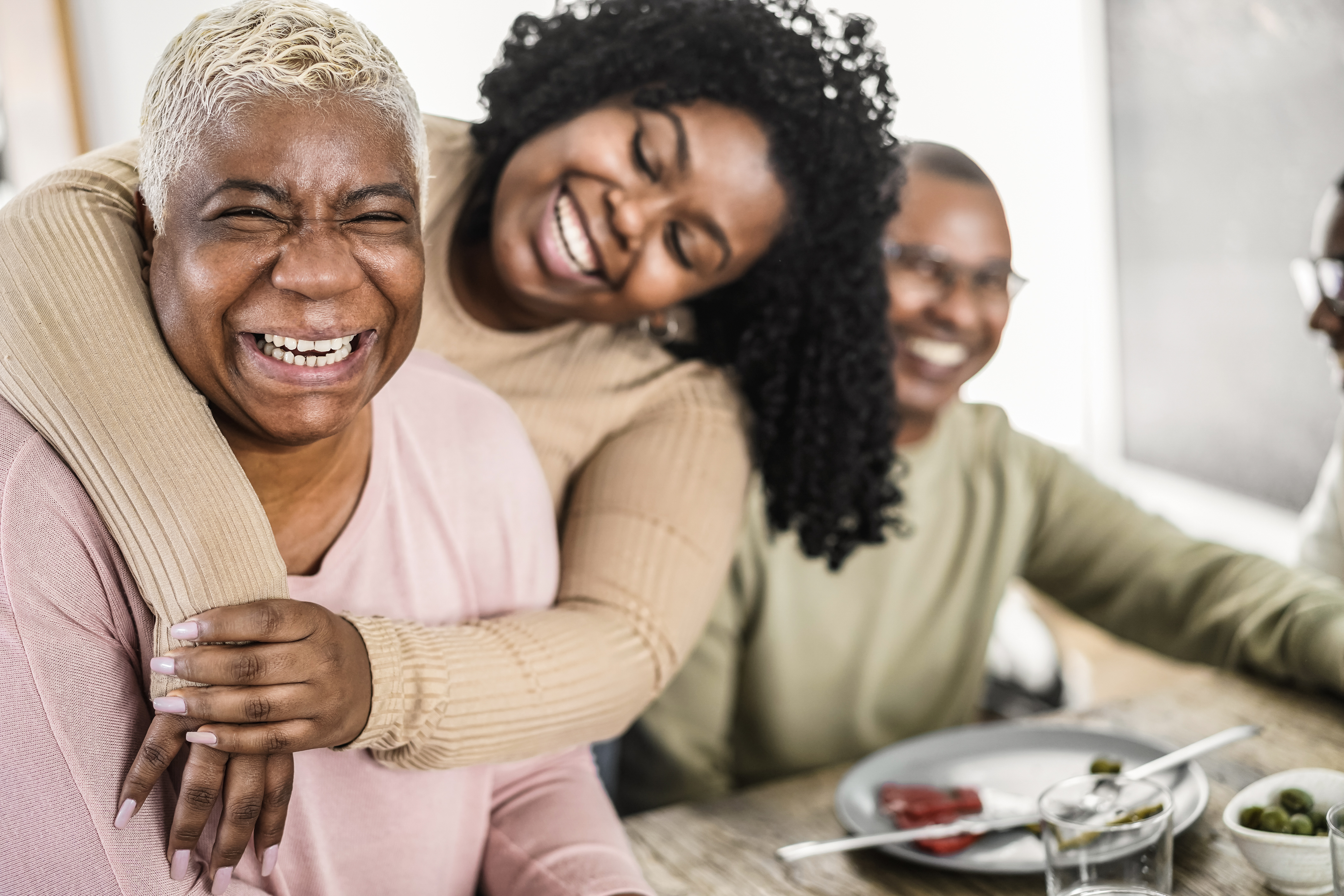 Happy black family eating lunch together at home - Main focus on mother face