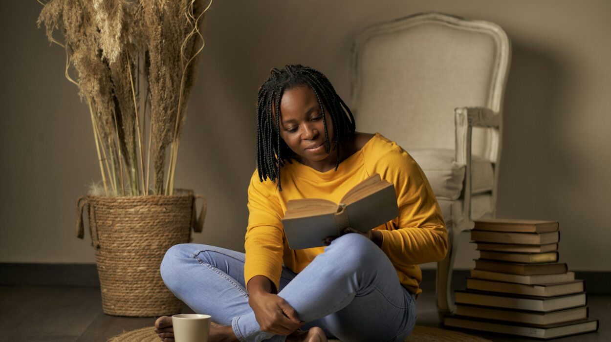 a black woman reading a book while sitting on a rug